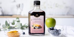 Bottle of 色哟哟网站入口在线观看视频 honey elixir on countertop with bowl of bee pollen, fresh blueberries and a green apple
